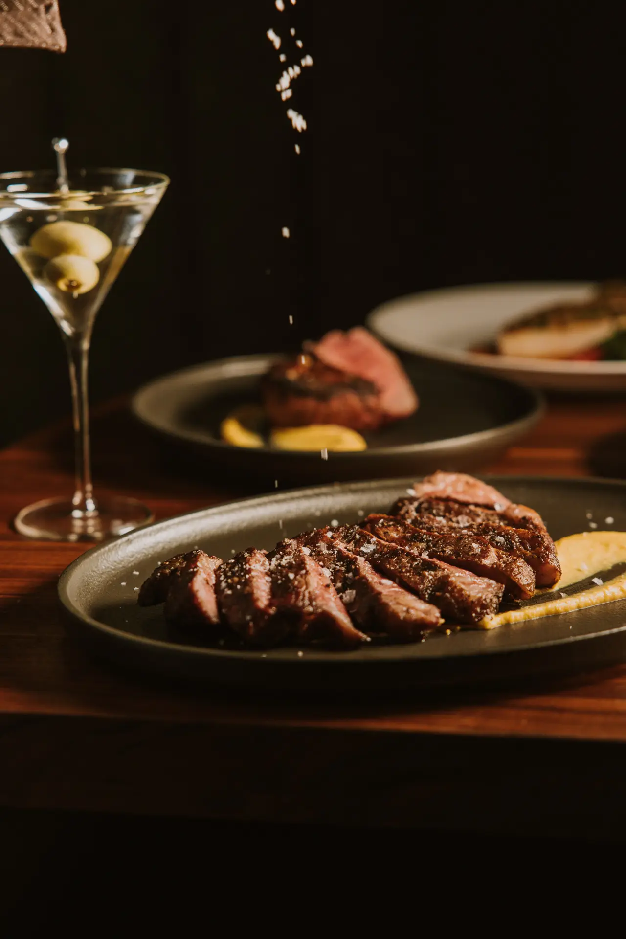 A martini beside sliced steak